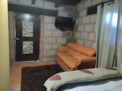 a living room with a brown couch and a brick wall at Rancho los olivos Habitaciones Campestres in San Miguel de Allende