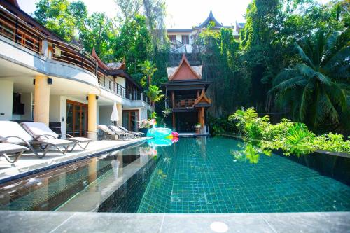 a swimming pool with chairs and a house at Luxury 4 bedrooms Villa with Seaview Infinity Pool overlooking Surin Beach in Surin Beach