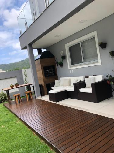 una terraza con sofá y sillas en una casa en Casa Luxo com piscina a 500 metros da praia en Florianópolis