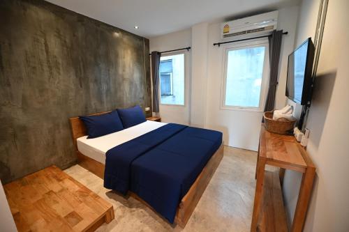 a bedroom with a bed with blue sheets and a tv at Sribumpen Plus in Bangkok
