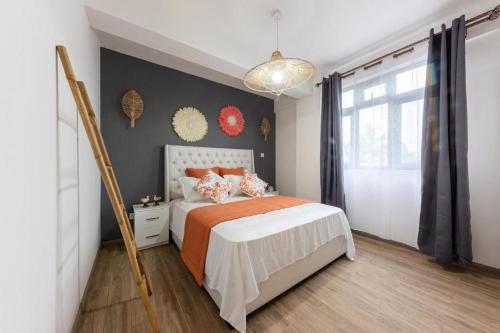 a bedroom with a bed with an orange and white bedspread at 373 Wolmar Cosy and Modern Apartment- 200 metres from the Beach and Supermarkets and just next to Domaine de wolmar with views of deers and green natural park in Flic-en-Flac