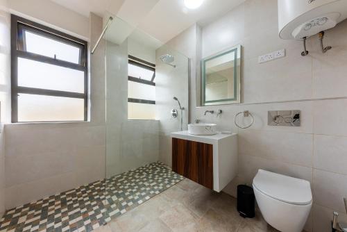 a white bathroom with a toilet and a sink at 373 Wolmar Cosy and Modern Apartment- 200 metres from the Beach and Supermarkets and just next to Domaine de wolmar with views of deers and green natural park in Flic-en-Flac