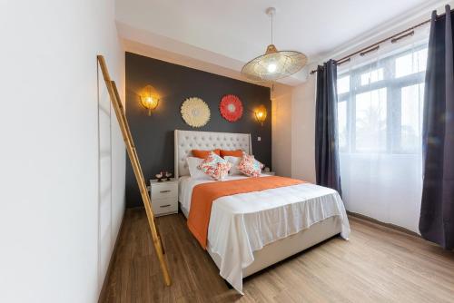a bedroom with a bed with an orange comforter at 373 Wolmar Cosy and Modern Apartment- 200 metres from the Beach and Supermarkets and just next to Domaine de wolmar with views of deers and green natural park in Flic-en-Flac