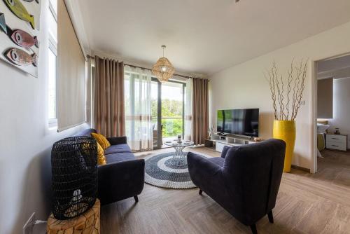 a living room with two couches and a tv at 373 Wolmar Cosy and Modern Apartment- 200 metres from the Beach and Supermarkets and just next to Domaine de wolmar with views of deers and green natural park in Flic-en-Flac