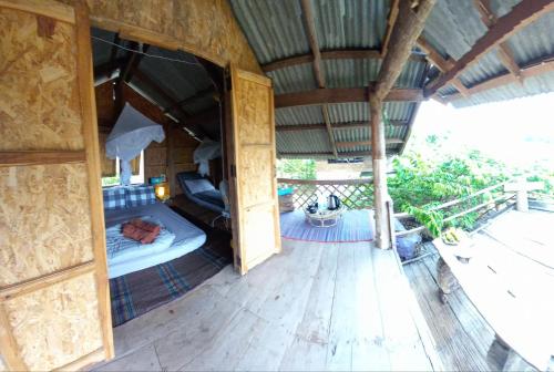 an outdoor room with a bed in a building at Chinopuu Hut Homestay Muangkong ชิโนปู ฮัท โฮมสเตย์ เมืองคอง เชียงดาว in Mueang Khong