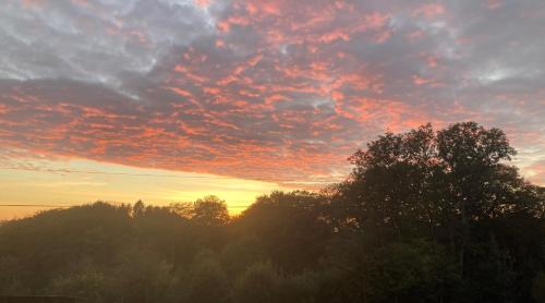 a sunset with trees and clouds in the sky at Le Gîte au bord de la Forêt in Monthermé