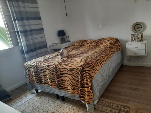 un gato sentado en una cama en un dormitorio en Charmosa casa em condominio com quintal en São Paulo