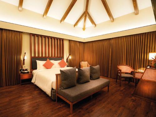 a bedroom with a bed and a chair and a table at Rosetta Sakleshpur in Sakleshpur