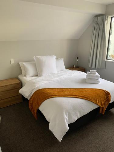 1 dormitorio con 1 cama grande con sábanas y almohadas blancas en Stylish Oasis in central city en Christchurch