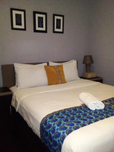 um quarto com uma cama grande e almofadas brancas em Acacia Guesthouse em Kempton Park