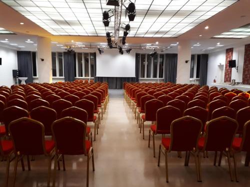an empty lecture hall with red chairs and a screen at Hotel Du Parc - Mulhouse Centre in Mulhouse