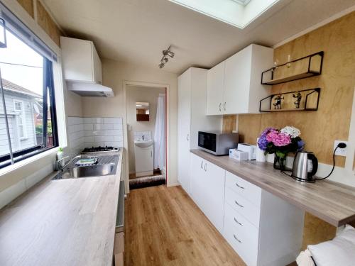 una cocina con armarios blancos y fregadero en Dunedin Luxurious Retreat Cabin en Dunedin