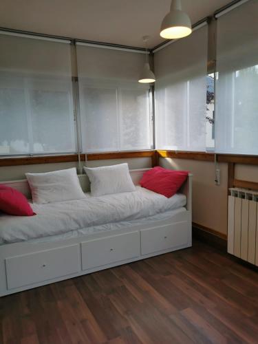 uma cama grande com duas almofadas vermelhas num quarto em Casita independiente con jardín y chimenea. em Cercedilla