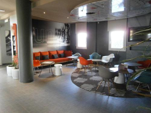 a lobby with a couch and tables and chairs at Ibis Sevilla in Seville