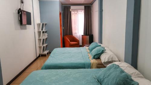 a room with two beds and a chair at Hotel Hoja de Oro Corcovado in Puerto Jiménez
