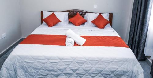 a large bed with red and white pillows on it at Lux Suites Milimani Luxe Apartments kisumu in Kisumu