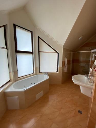 y baño con bañera, lavabo y ventanas. en Шале Bellmont, en Palyanytsya