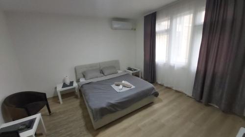a bedroom with a bed and a chair and a window at Apartman Pavlovic in Leskovac