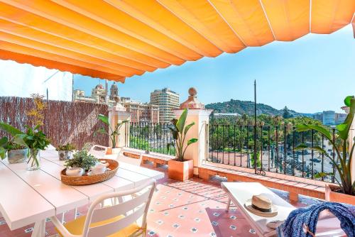 eine Terrasse mit einem Tisch und Stühlen auf dem Balkon in der Unterkunft Genteel Home Plaza de la Marina in Málaga