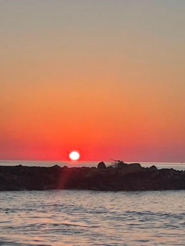 a sunset on a rocky island in the ocean at Coralli Beach Hotel in Kokkini Khanion