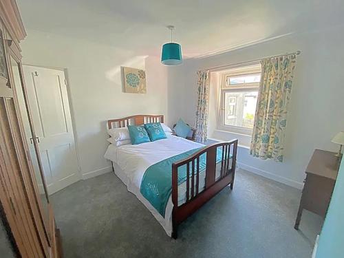 a bedroom with a bed with blue pillows and a window at The Retreat @ The Old Smithy, Colebrook Village in Plymouth