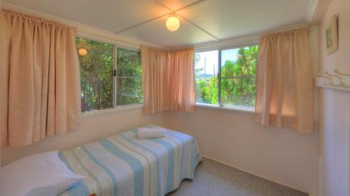 een slaapkamer met een bed en 2 ramen bij The Vines Motel & Cottages in Stanthorpe