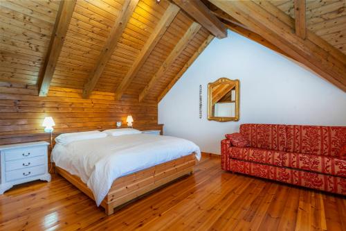 a bedroom with a bed and a red couch at Panoramic House Carnia - Mountain View APT with Parking and Terraces in Ligosullo
