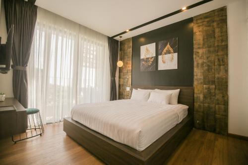 um quarto com uma grande cama branca e uma janela em Fati Boutique Hotel & Apartment em Vung Tau