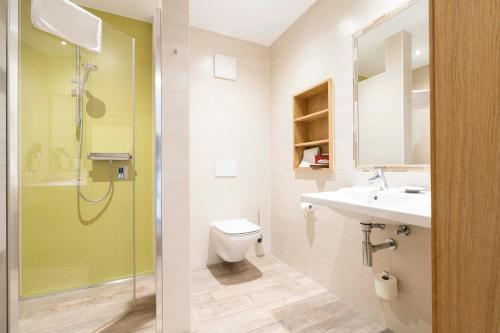 a bathroom with a toilet and a sink and a shower at Hotel Brauerei Gasthof Höhn in Memmelsdorf