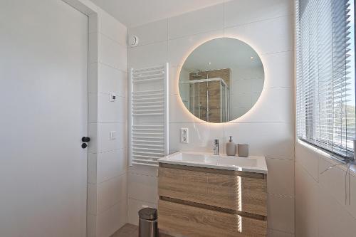 ein Bad mit einem Waschbecken und einem Spiegel in der Unterkunft Vakantiehuis Poldertje 1A - Baddomburg in Domburg