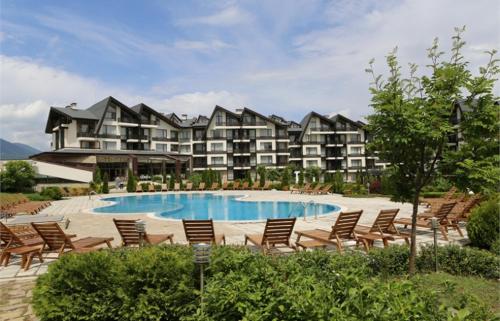 een resort met een zwembad en stoelen en een gebouw bij Bright Studio in a Spacious Complex in the Valley by Flat Mаnager in Bansko