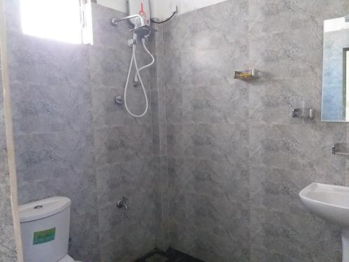 a bathroom with a shower with a toilet and a sink at Villa Sunrise in Induruwa