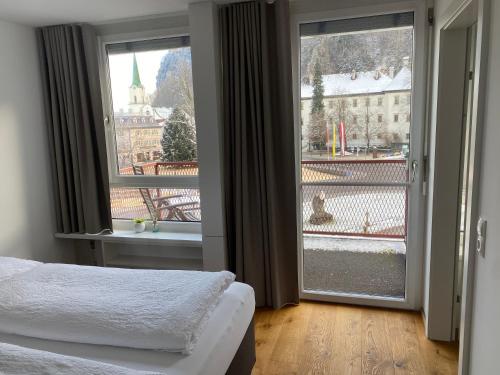 a bedroom with a bed and a large window at Zimmer & Appartements am Schloßplatz in Hohenems