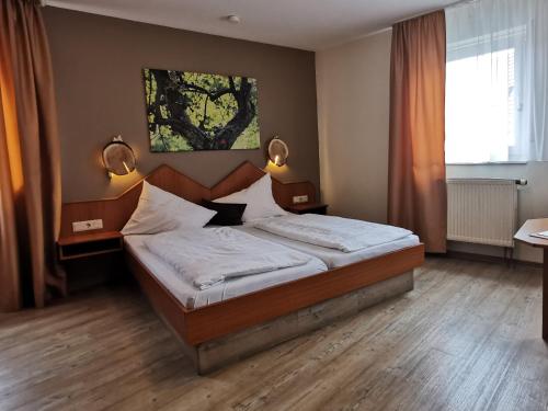 a bedroom with a bed with two lamps on the wall at Gasthaus & Hotel Drei Lilien in Werbach