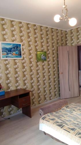 a bedroom with a bed and a desk and a wall at Квартира у моря in Odesa