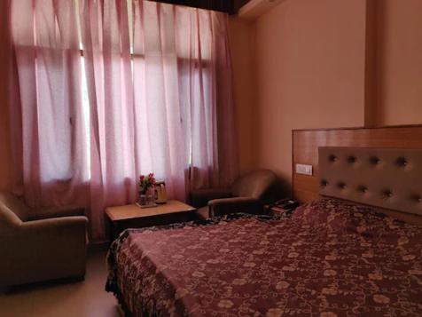 1 dormitorio con 1 cama, 1 silla y 1 ventana en HOTEL MOUNTAIN VIEW, en Jyotirmath