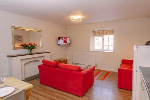 a living room with red chairs and a fireplace at Corffe House and Holiday Cottages in Barnstaple