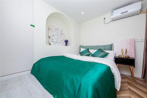 a bedroom with a bed with a green blanket at Baihong Riverview Apartment-Hongya Cave in Chongqing