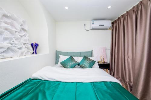 a bedroom with a bed with a green and white blanket at Baihong Riverview Apartment-Hongya Cave in Chongqing