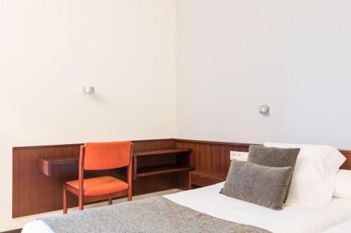 a bedroom with a bed and a chair and a desk at Hotel Emporda in Figueres
