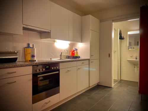 a kitchen with white cabinets and a stove top oven at Spielzimmer am Bodensee in Rorschach