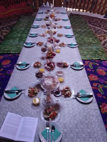 a long table with plates and glasses of food on it at Guesthouse Kishimzhan in Talas