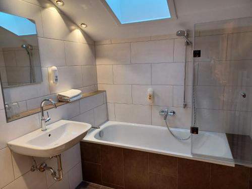 a bathroom with a sink and a tub and a mirror at Gästehaus Gritscher in Josefsthal