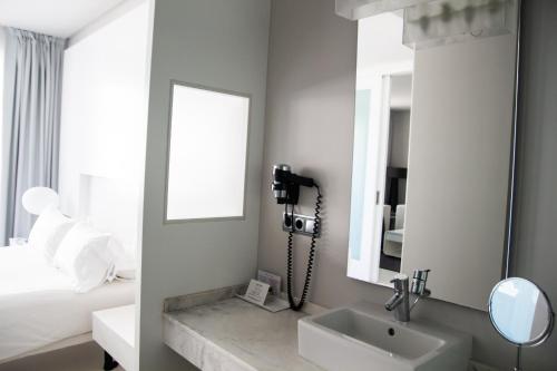 a bathroom with a sink, mirror, and bathtub at Maroa Hotel in Vigo