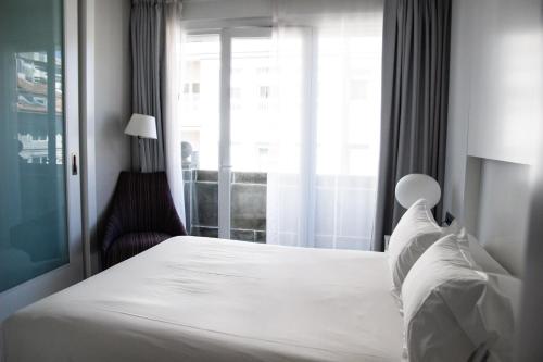 a bedroom with a white bed and a window at Hotel Maroa Vigo in Vigo