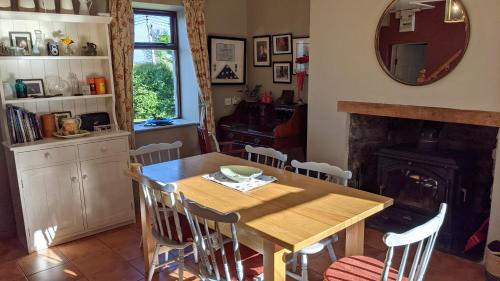 une salle à manger avec une table en bois et une cheminée dans l'établissement James Tymon Self-Catering Cottage, à Gorteen