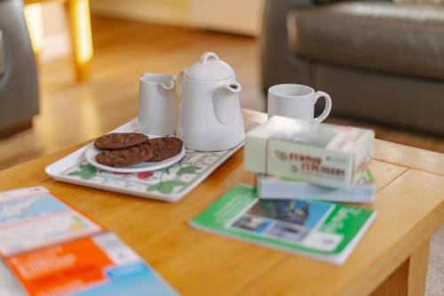 a coffee table with a plate of cookies and a tea set at Corffe House and Holiday Cottages in Barnstaple