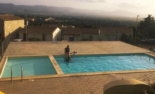 Un uomo in piedi in una piscina in una casa di Superbe appartement dans petite résidence . a Badesi