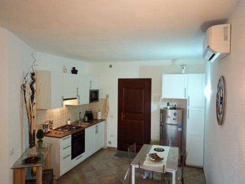 eine Küche mit weißen Schränken und einem Tisch darin in der Unterkunft Superbe appartement dans petite résidence . in Badesi