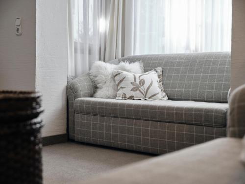 a couch with a pillow in front of a window at Appartements Erwin & Eleonore Hüttl I in Neukirchen am Großvenediger